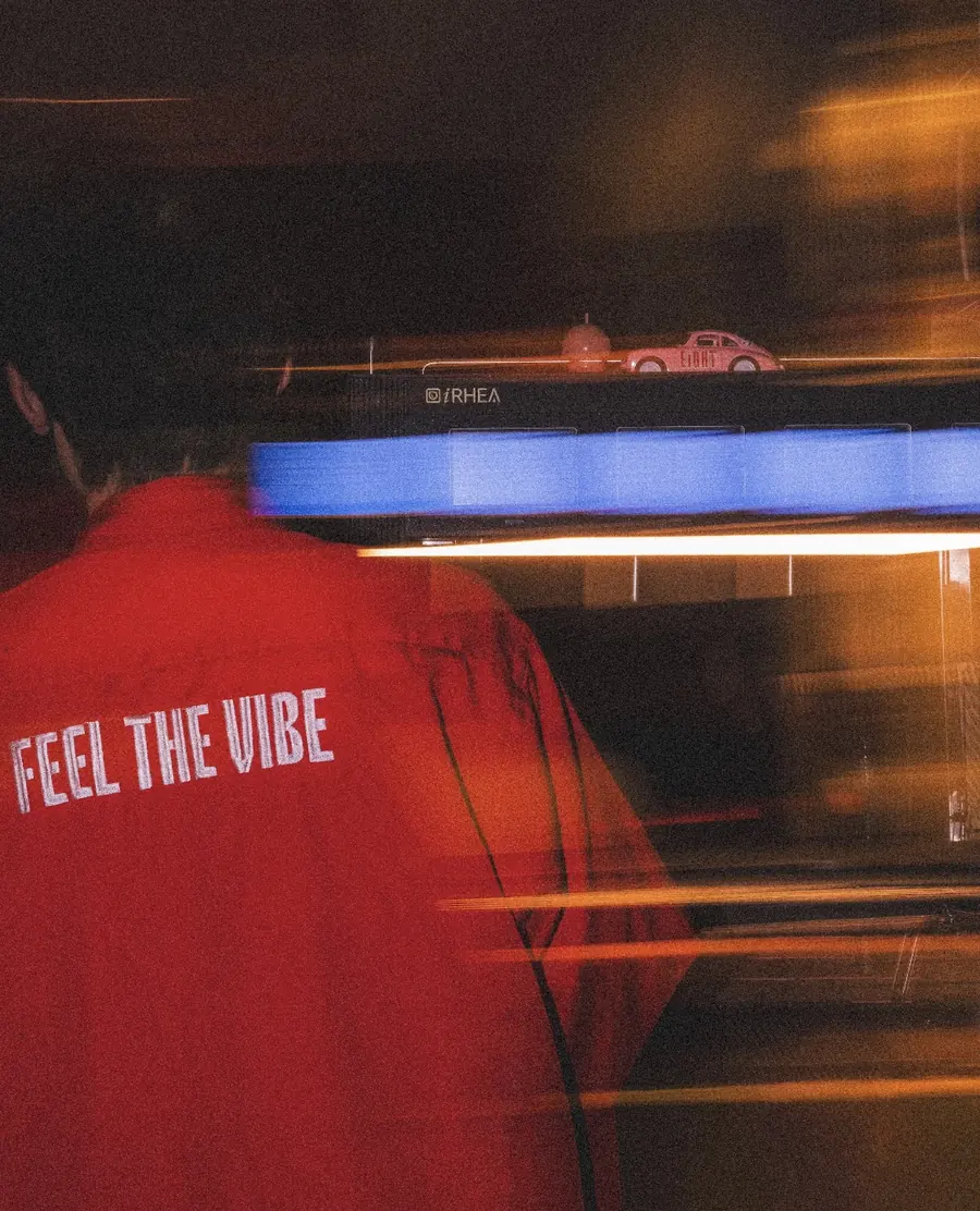شخص بقميص ايت الأحمر مكتوب على ظهره FEEL THE VIBE داخل المقهى